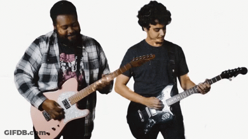 A Man In A Plaid Shirt Is Playing A Guitar Next To Another Man GIF
