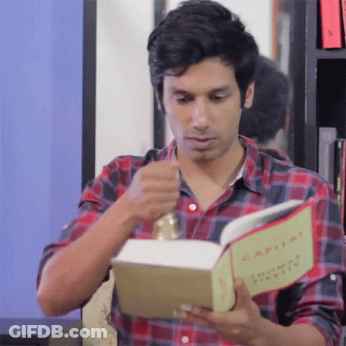 A Man In A Plaid Shirt Is Reading The Book Capital GIF