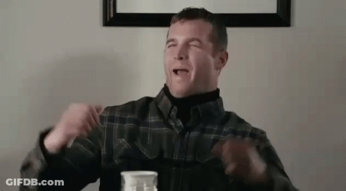 A Man In A Plaid Shirt Is Sitting At A Table With A Bottle Of Milk In Front Of Him . GIF