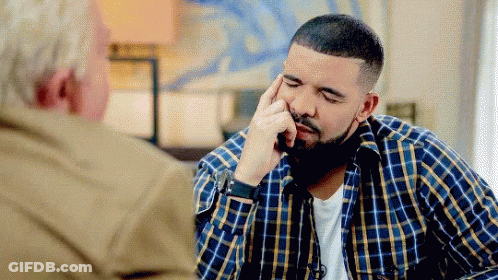 A Man In A Plaid Shirt Is Sitting At A Table With A Man In A Tan Jacket . GIF