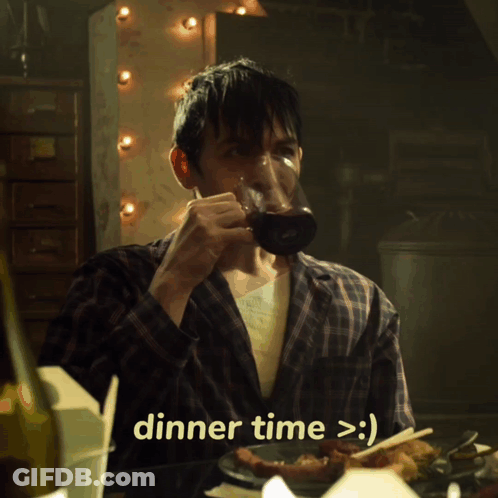 A Man In A Plaid Shirt Is Sitting At A Table With A Plate Of Food And Says Dinner Time > :) GIF