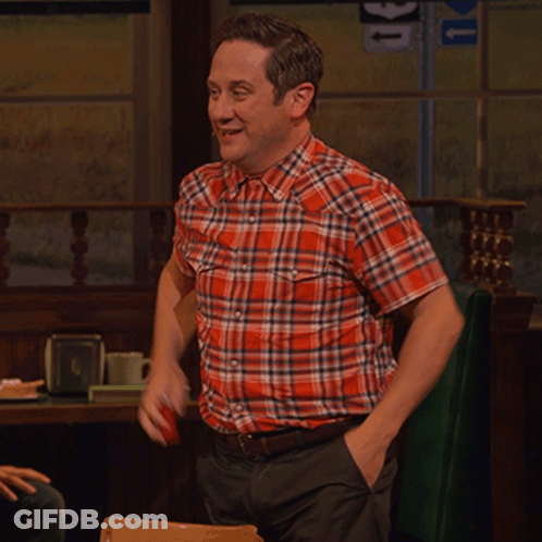 A Man In A Plaid Shirt Is Sitting At A Table With A Sign That Says U On It GIF