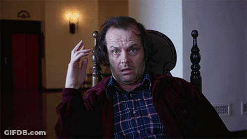A Man In A Plaid Shirt Is Sitting In A Chair And Making A Funny Face GIF