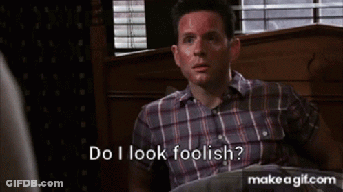 A Man In A Plaid Shirt Is Sitting In A Chair And Says Do I Look Foolish ? GIF