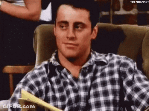 A Man In A Plaid Shirt Is Sitting In A Chair With A Piece Of Paper In His Hand . GIF