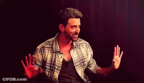 A Man In A Plaid Shirt Is Sitting In A Chair With His Hands Outstretched . GIF