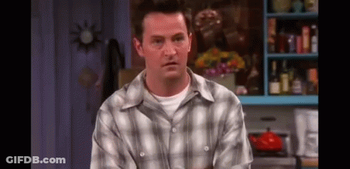 A Man In A Plaid Shirt Is Sitting In A Kitchen Looking At The Camera . GIF