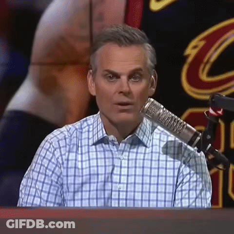 A Man In A Plaid Shirt Is Sitting In Front Of A Microphone And Making A Funny Face . GIF
