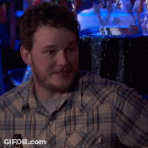 A Man In A Plaid Shirt Is Sitting In Front Of A Table With Flowers On It GIF