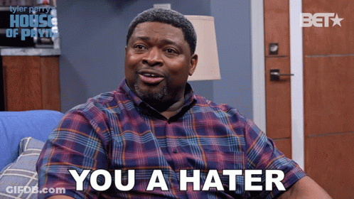 A Man In A Plaid Shirt Is Sitting On A Blue Couch And Says " You A Hater " GIF