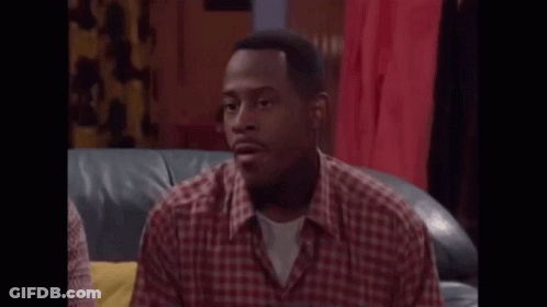 A Man In A Plaid Shirt Is Sitting On A Couch And Talking . GIF