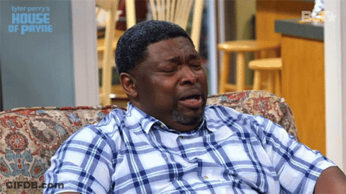 A Man In A Plaid Shirt Is Sitting On A Couch With The Words Tyler Perry 'S House Of Payne GIF
