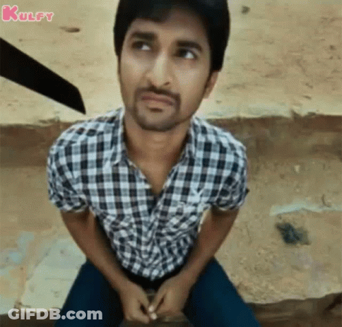 A Man In A Plaid Shirt Is Sitting On The Ground Looking Up . GIF