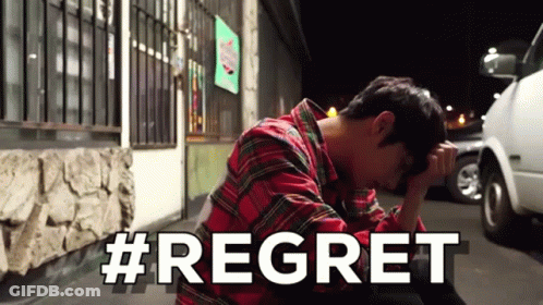 A Man In A Plaid Shirt Is Sitting On The Ground With His Head In His Hands And The Word Regret Written In White Letters GIF