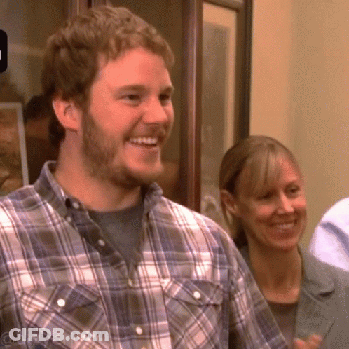 A Man In A Plaid Shirt Is Smiling While A Woman Looks On GIF