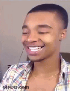 A Man In A Plaid Shirt Is Smiling With His Eyes Closed GIF