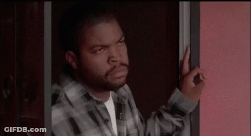 A Man In A Plaid Shirt Is Standing In A Doorway And Making An Okay Sign . GIF