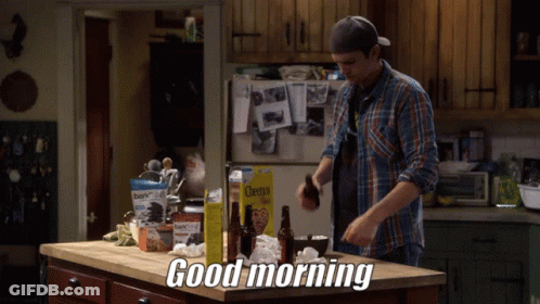 A Man In A Plaid Shirt Is Standing In A Kitchen With A Box Of Cheerios On The Counter GIF