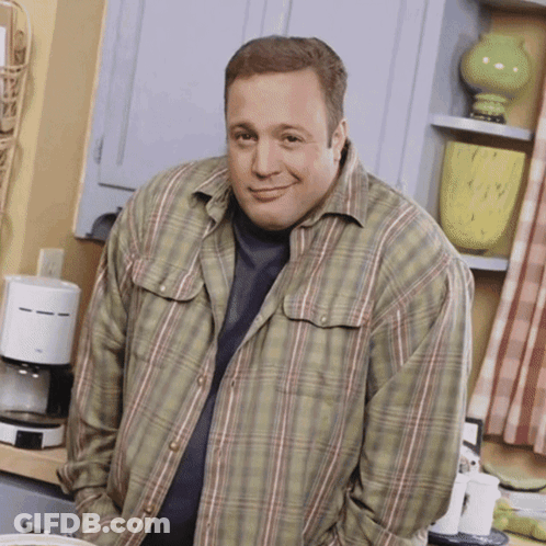 A Man In A Plaid Shirt Is Standing In A Kitchen With His Hands In His Pockets GIF