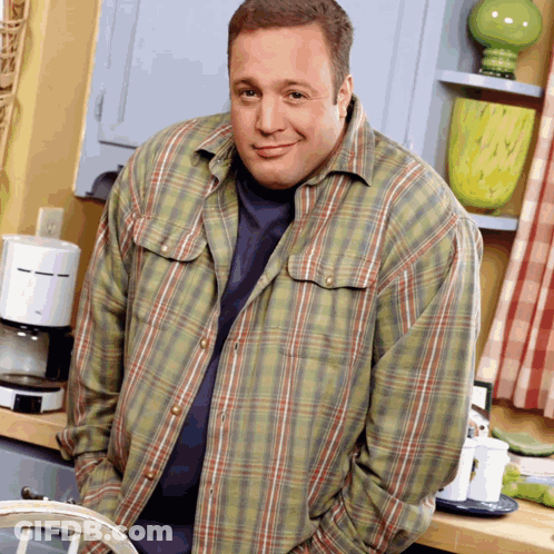 A Man In A Plaid Shirt Is Standing In Front Of A Coffee Maker GIF