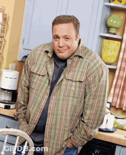 A Man In A Plaid Shirt Is Standing In Front Of A Coffee Maker GIF