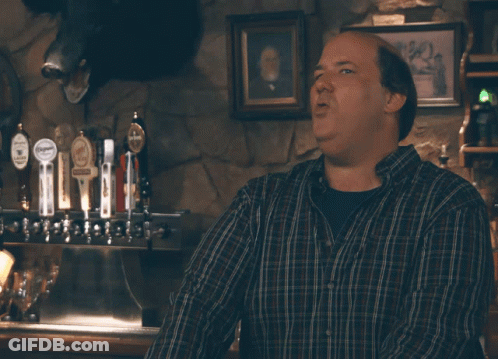 A Man In A Plaid Shirt Is Standing In Front Of A Sign That Says Well Well Well GIF