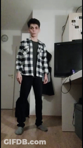 A Man In A Plaid Shirt Is Standing In Front Of A Television GIF