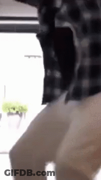 A Man In A Plaid Shirt Is Standing In Front Of A Window And Dancing . GIF