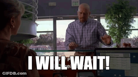 A Man In A Plaid Shirt Is Standing In Front Of A Woman In An Office And Says `` I Will Wait ! '' GIF