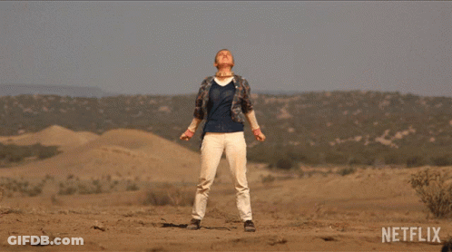 A Man In A Plaid Shirt Is Standing In The Desert With A Netflix Logo In The Corner GIF
