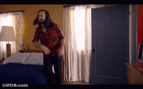 Man In Plaid Shirt Standing Next To Bed GIF