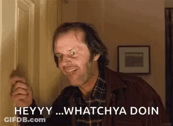 A Man In A Plaid Shirt Is Standing Next To A Door And Smiling . GIF