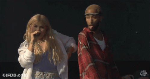 A Man In A Plaid Shirt Is Standing Next To A Woman In A White Shirt That Says Hayley Bravo On The Bottom GIF