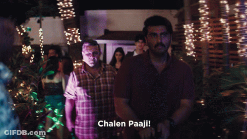 A Man In A Plaid Shirt Is Standing Next To Another Man With The Words Chalen Paaji Written Below Him GIF