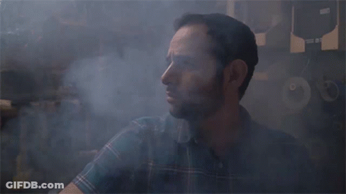 A Man In A Plaid Shirt Is Surrounded By Smoke And A Sign That Says ' A ' On It GIF