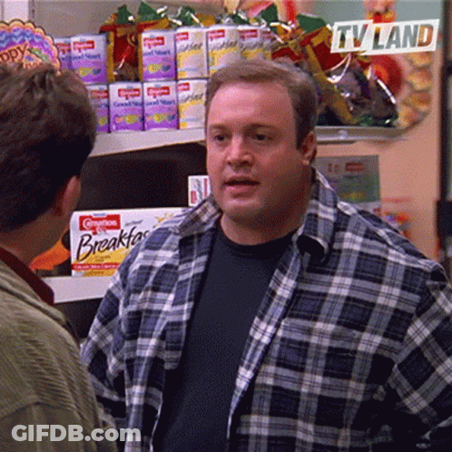 A Man In A Plaid Shirt Is Talking To Another Man In A Grocery Store With A Sign That Says Tv Land GIF
