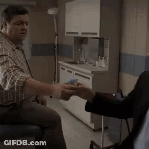 A Man In A Plaid Shirt Is Talking To Another Man In A Kitchen GIF