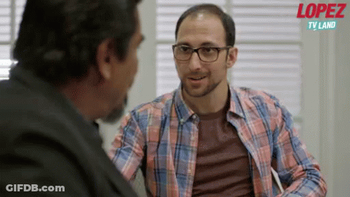 A Man In A Plaid Shirt Is Talking To Another Man With The Words Lopez Tv Land Behind Him GIF