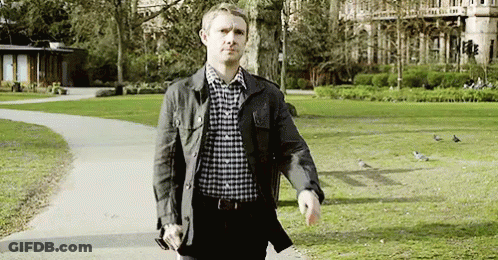 A Man In A Plaid Shirt Is Walking Through A Park . GIF