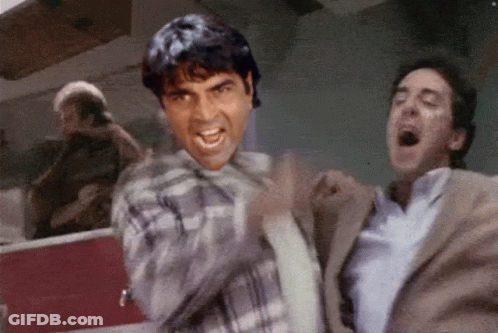 A Man In A Plaid Shirt Is Yelling At Another Man GIF
