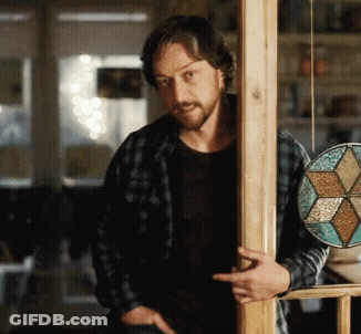 A Man In A Plaid Shirt Leans Against A Wooden Pole GIF