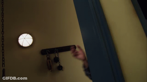 A Man In A Plaid Shirt Reaches Out His Hand Towards The Camera GIF