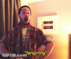 A Man In A Plaid Shirt Says " Fangirling " In A Room GIF
