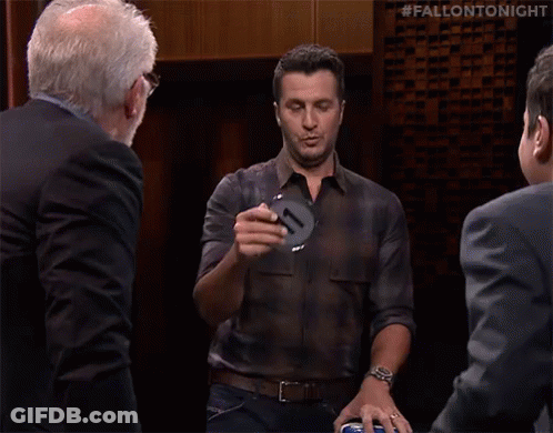 A Man In A Plaid Shirt Says Ruh Roh In Front Of A Group Of Men GIF