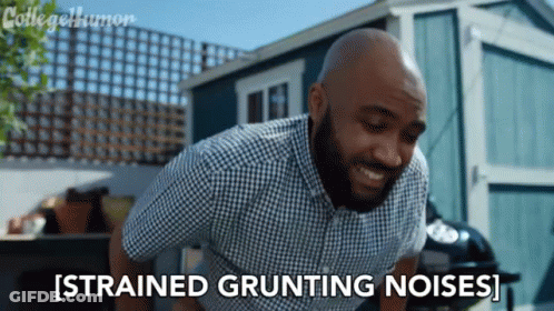 A Man In A Plaid Shirt Says Strained Grunting Noises In Front Of A Shed GIF