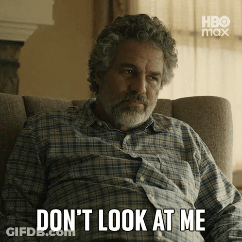 A Man In A Plaid Shirt Sits In A Chair With The Words " Don 'T Look At Me " Written Below Him GIF