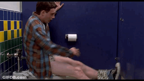 A Man In A Plaid Shirt Sits On A Toilet With His Pants Down GIF