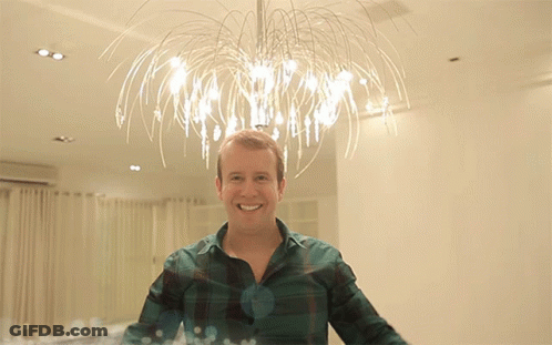 Man In Plaid Shirt Smiling In Front Of Chandelier GIF