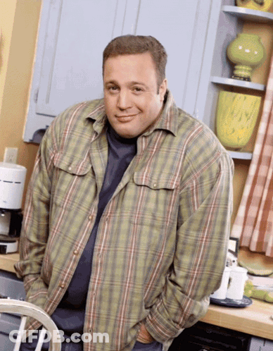 A Man In A Plaid Shirt Stands In A Kitchen GIF