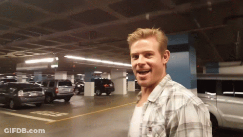 A Man In A Plaid Shirt Stands In A Parking Garage With A Stop Sign On The Ground GIF